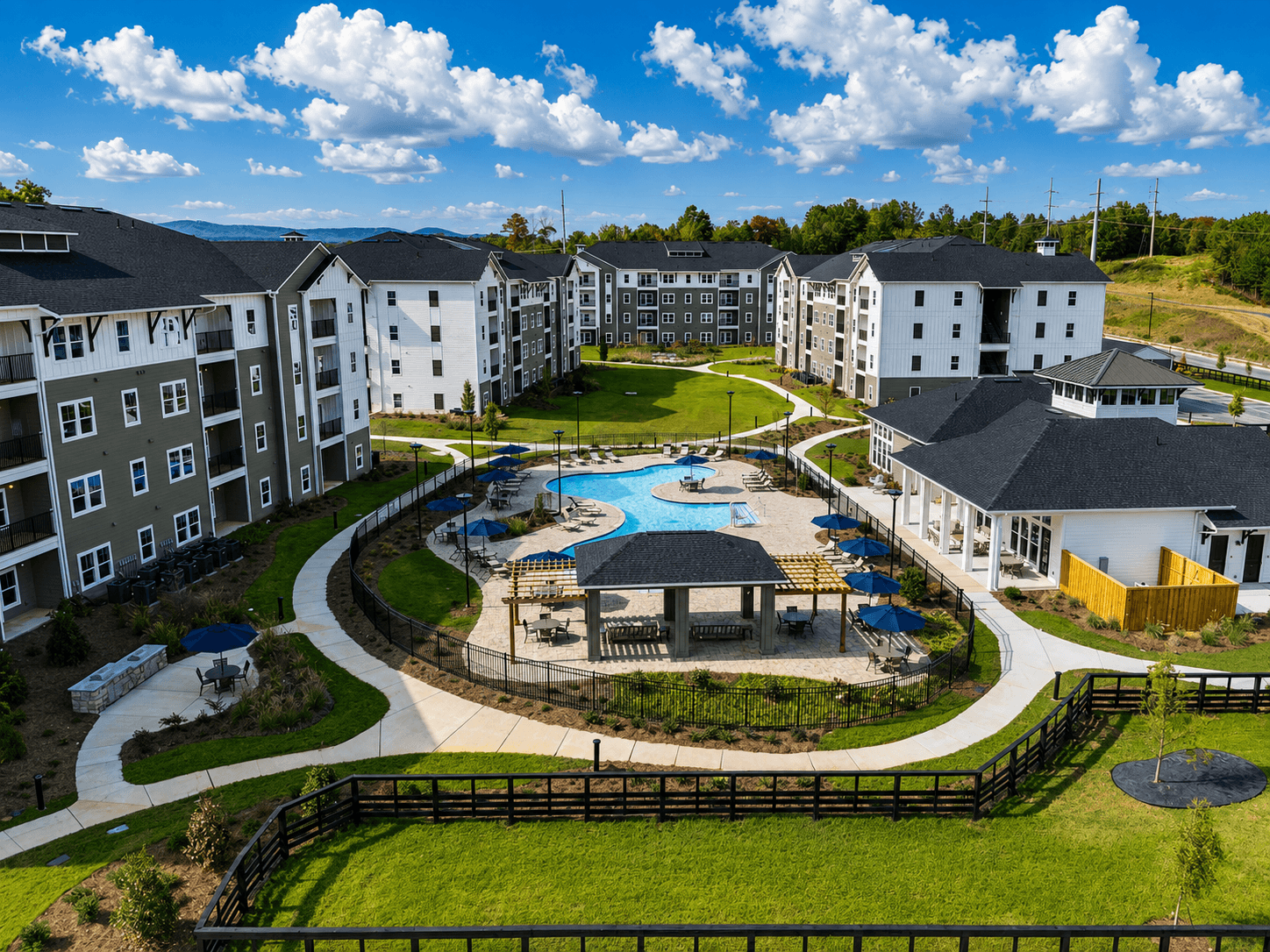 A large apartment complex with a pool and a fenced in area.